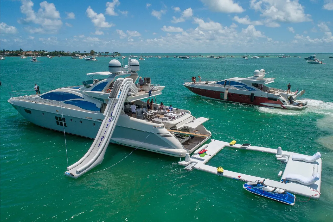 Side aerial view of the yacht
  with all features deployed, including slide, pool, and jet ski